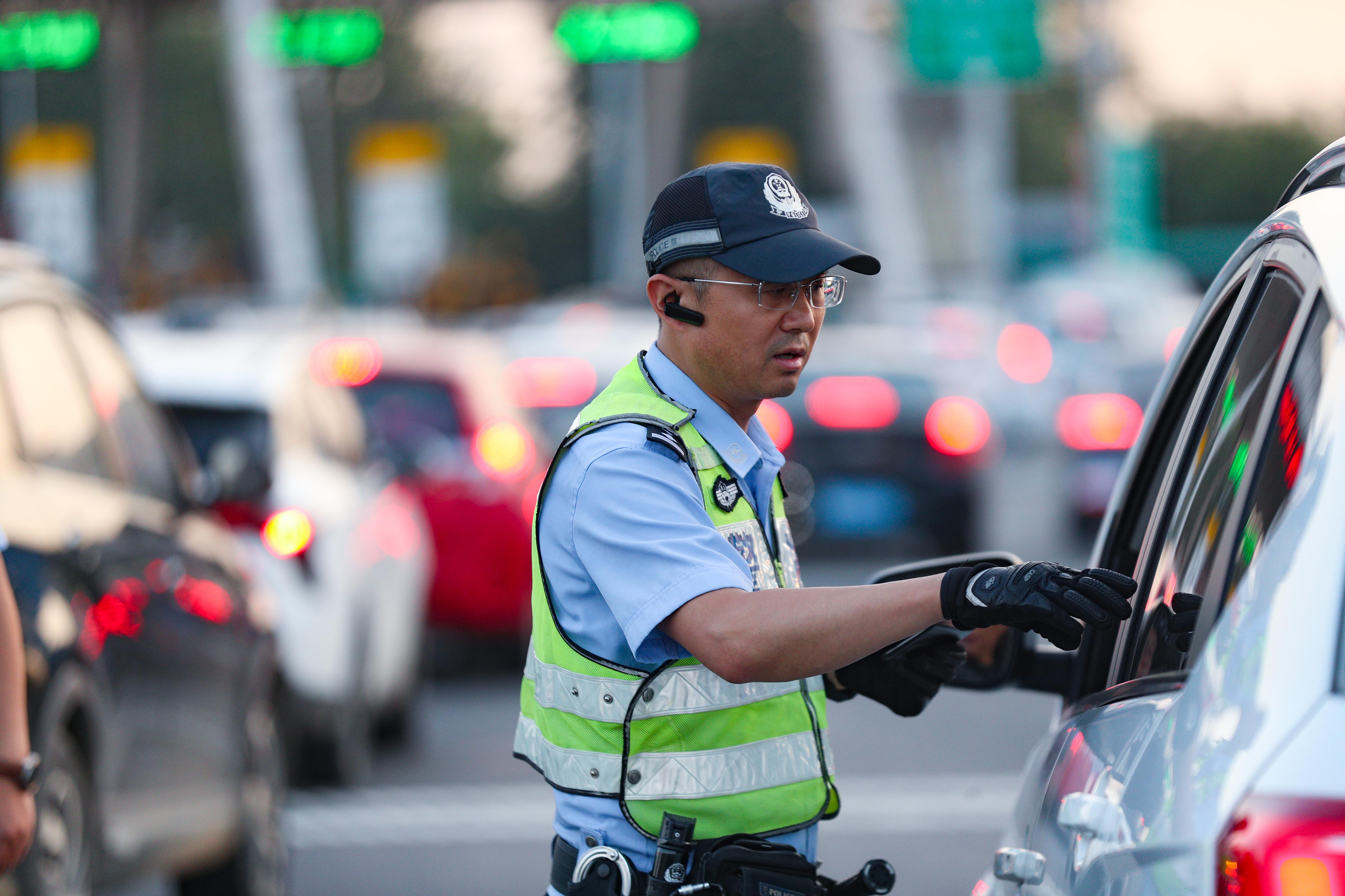 炎炎夏日，許俊富在高速公路出口的車流中提示過往司機(jī)注意安全.jpg